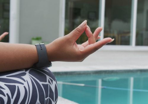 african-american-plus-size-woman-practicing-yoga-sitting-meditating-next-to-swimming-p-SBI-349486587